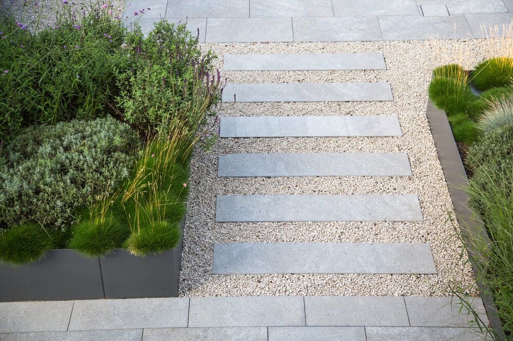 Modern stone plank walkway set in gravel between planted borders