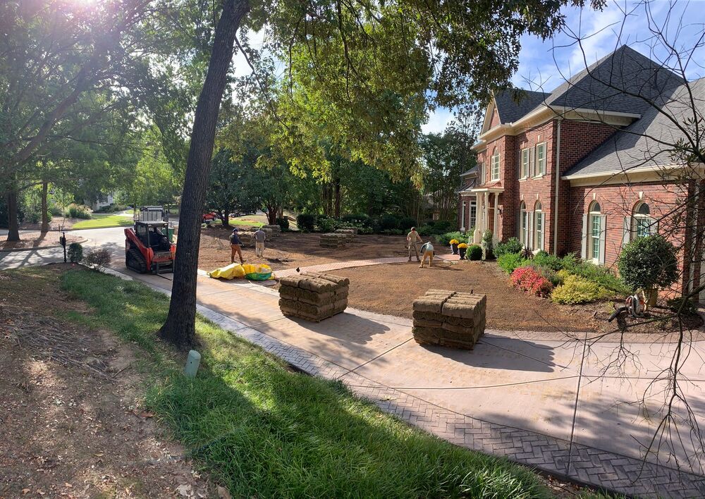 Sod installation in progress with fresh pallets staged on the drive