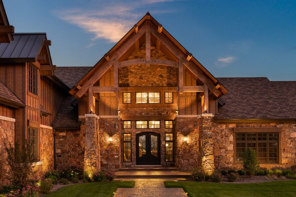 Timber-frame entryway with warm architectural and landscape lighting at dusk