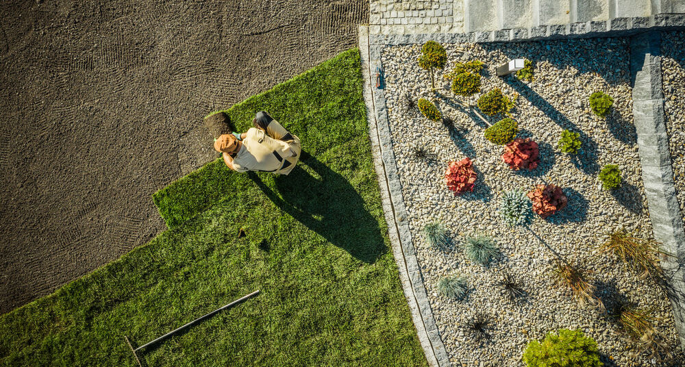 Aerial view of a freshly planted landscape bed with colorful flowers and shrubs bordering a manicured green lawn
