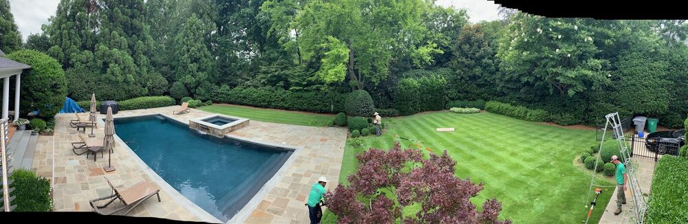 Manicured backyard with an in-ground pool, trimmed lawn and landscaped borders on a high-end residential property